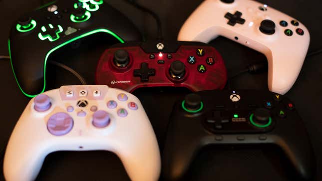 Five controllers for Xbox and PC are laid out on a rubber mat.